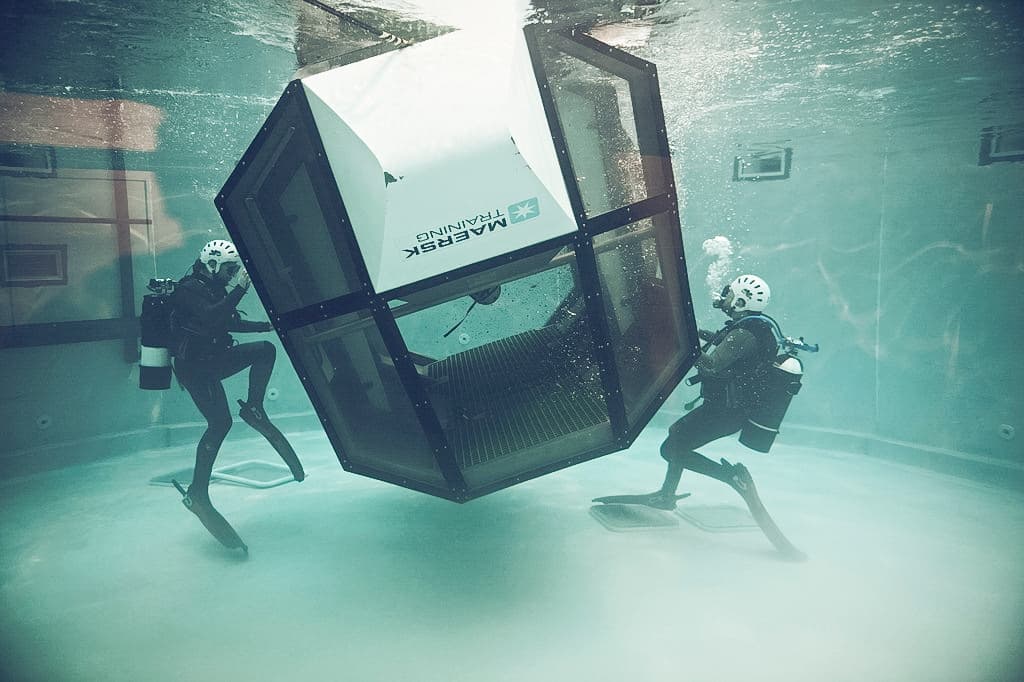 two divers in a controlled underwater environment conducting a training exercise with a helicopter simulator with the Maersk training logo