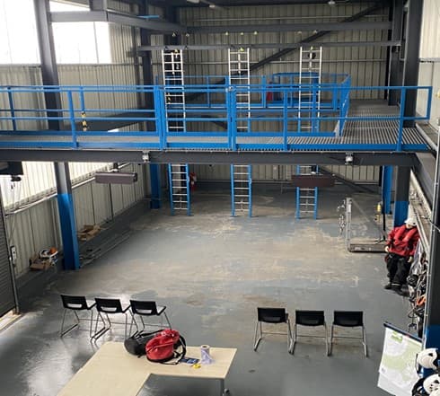 Indoor training facility equipped with ladders and safety gear, designed for hands-on instruction in height safety and rescue techniques.