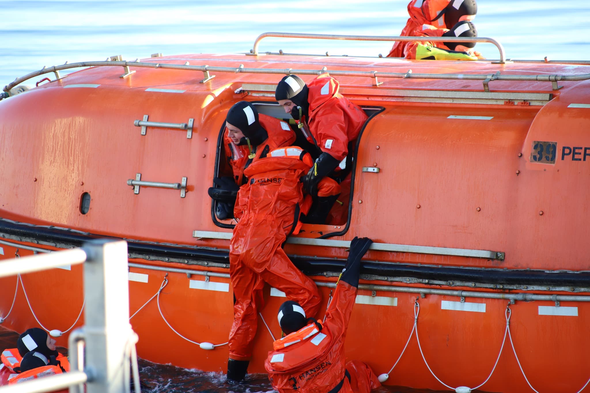 Trainees practising emergency evacuation by boarding a lifeboat, simulating real-life offshore escape scenarios to build confidence and readiness.
