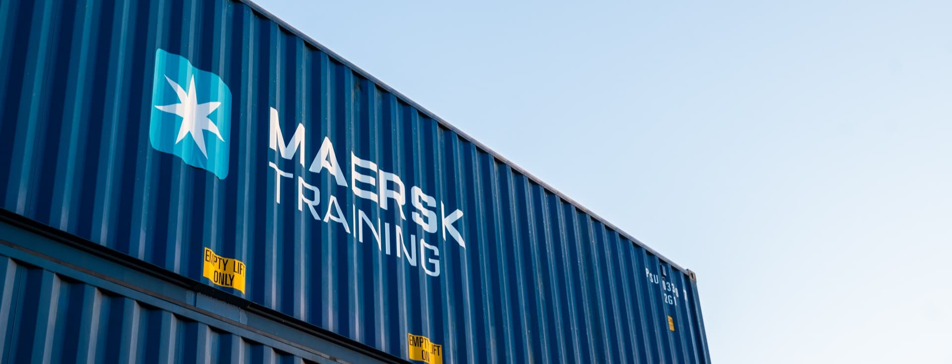 a blue shipping container with the Maersk Training logo prominently displayed on its side.