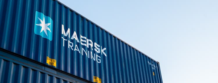 a blue shipping container with the Maersk Training logo prominently displayed on its side.