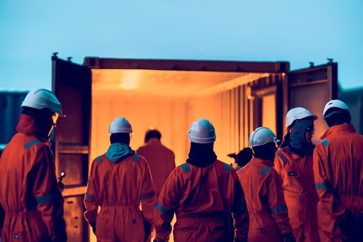 Trainees approach a lit safety training module, simulating emergency scenarios to enhance preparedness and teamwork in challenging environments.